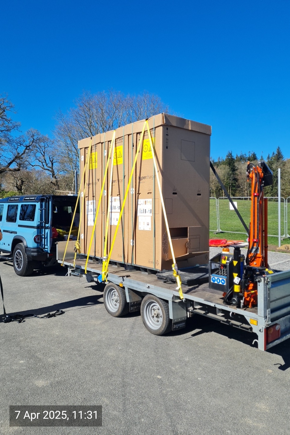 Crated EV chargers strapped to a HIAB trailer ready for transport