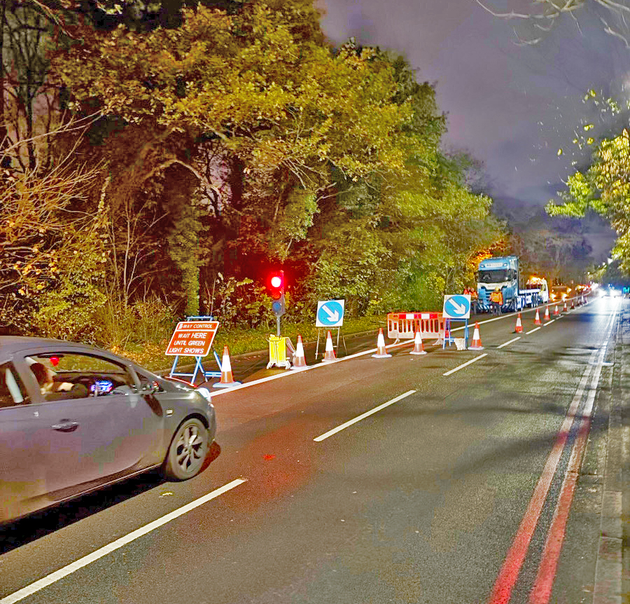 Night-time two-way traffic light system set up beside a low loader