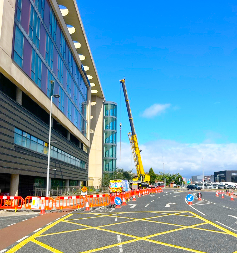 Mobile crane set up on a closed carriageway alongside a hospital building