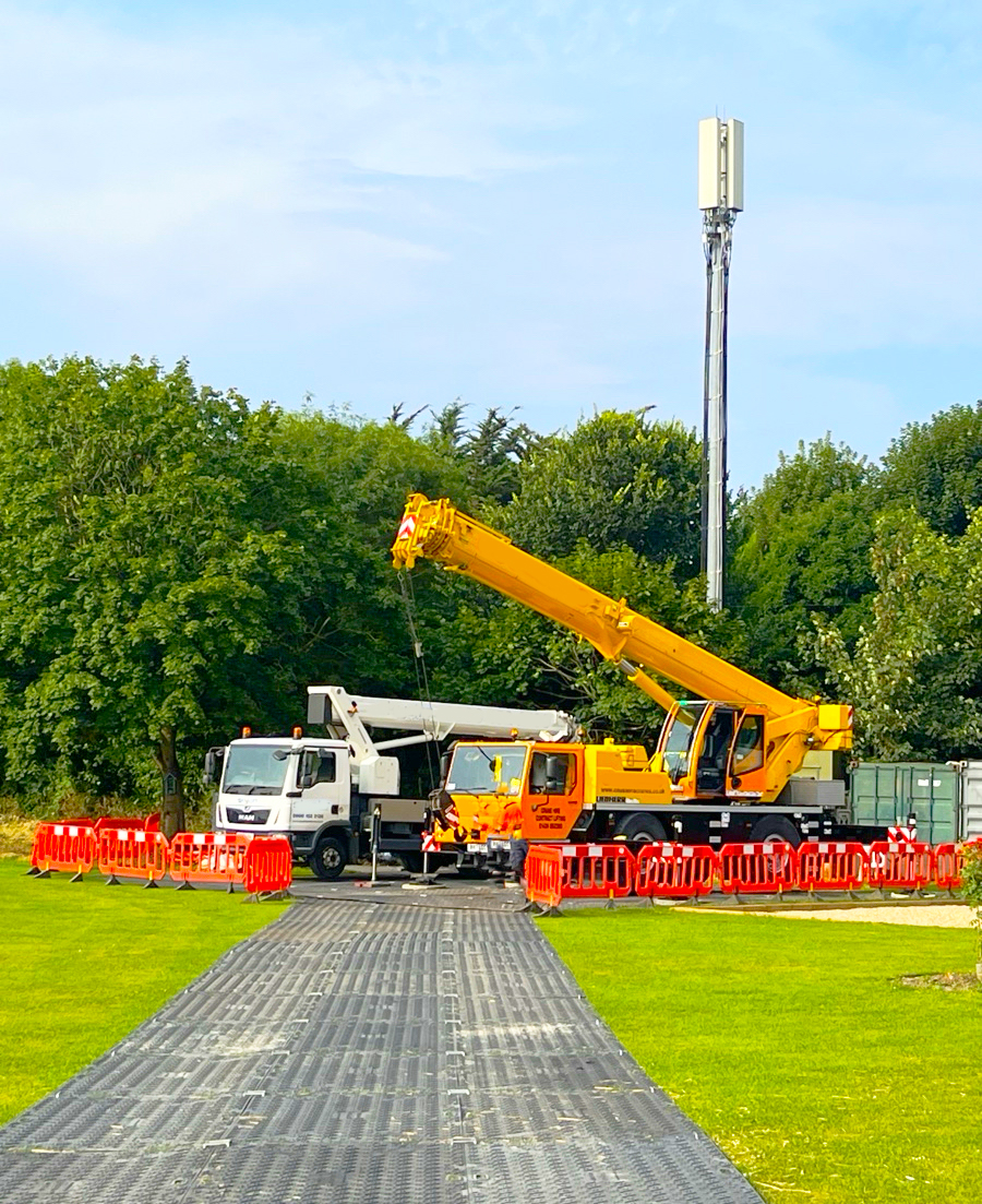 Mobile crane and MEWP set up on trackway matting beside a telecoms mast