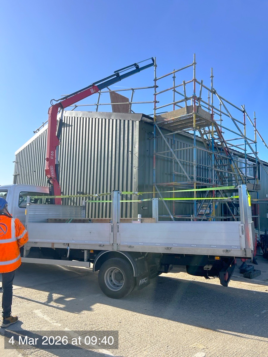 Lorry-mounted HIAB delivering materials to a scaffolded building
