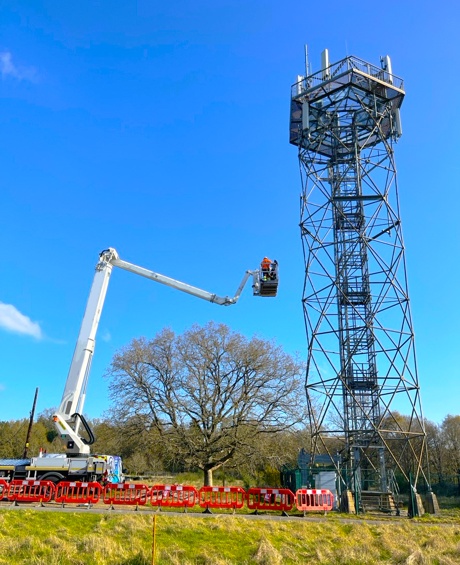Truck-mounted MEWP working at height on a lattice telecoms tower